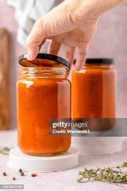 hand of woman opening tomato sauce jar's lid - tomato paste stock pictures, royalty-free photos & images