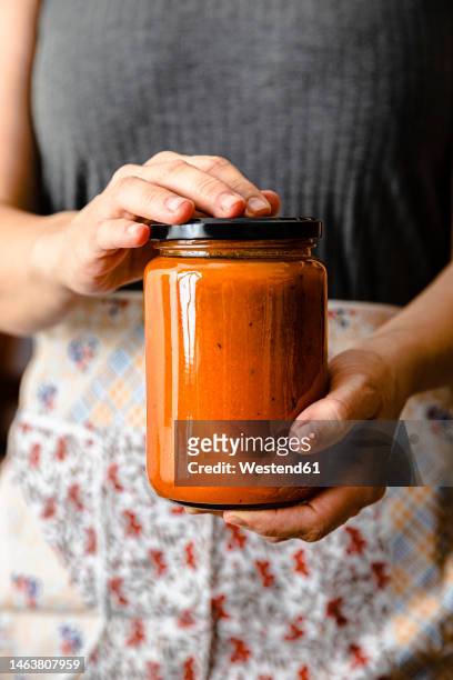 hands of mature woman holding homemade tomato sauce jar - tomato paste stock pictures, royalty-free photos & images
