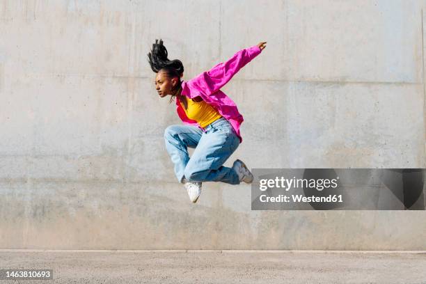 dancer jumping in front of wall on sunny day - dança moderna imagens e fotografias de stock