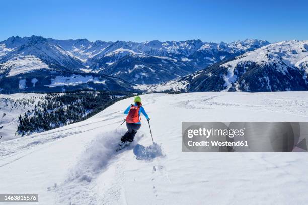 austria, tyrol, female skier sliding down snowcapped slope in kitzbuhel alps - kitzbühel stock-fotos und bilder