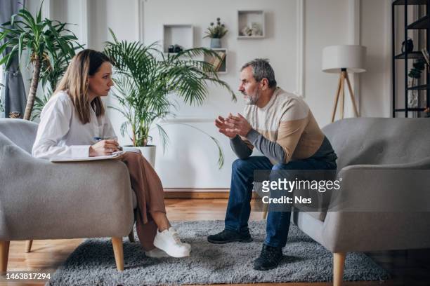 psicoterapia, joven doctora hablando con un hombre mayor - terapia fotografías e imágenes de stock