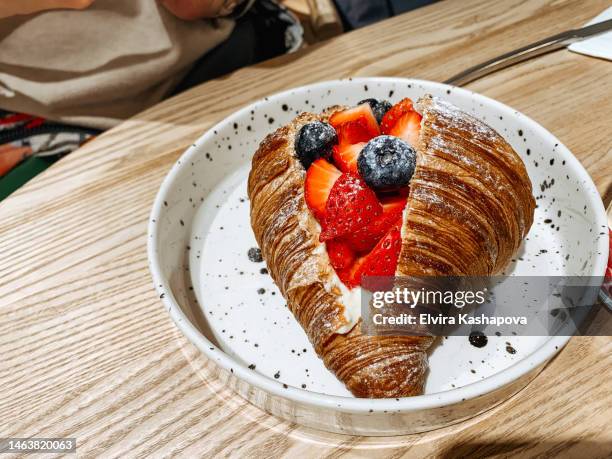 large croissant with strawberries and blueberries and custard on a plate - dessert topping stock pictures, royalty-free photos & images