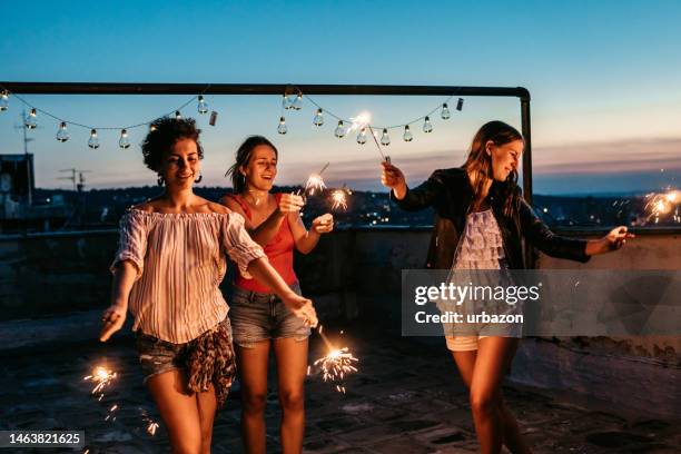 three female friends having a party on the rooftop with sparklers - terraced field stock pictures, royalty-free photos & images