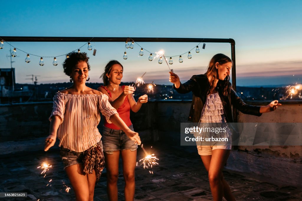 Three Female Friends Having A Party On The Rooftop With Sparklers