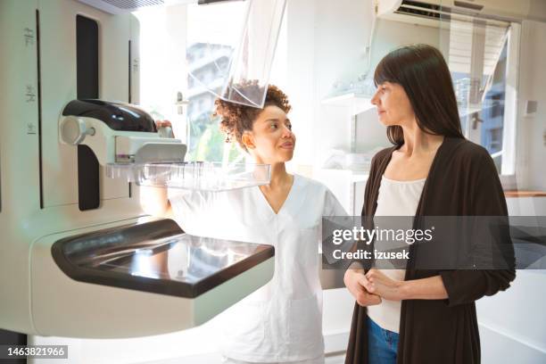 female doctor talking to patient during mammography test in examination room - mammografi bildbanksfoton och bilder