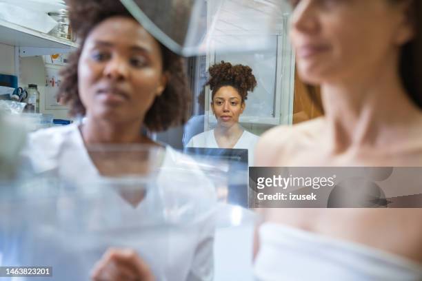 nurse talking to patient during mammography test in examination room - mammogram diversity stock pictures, royalty-free photos & images