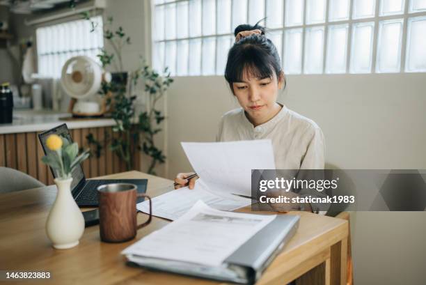 frau arbeitet zu hause. und während einer online-beratung mit einem steuerberater. - asian woman reading stock-fotos und bilder