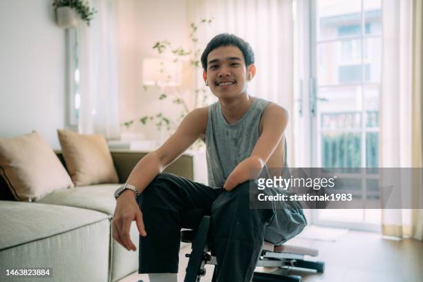 young man with prosthetic doing doing sit-up exercise on yoga mat at home. - amputee stock pictures, royalty-free photos & images