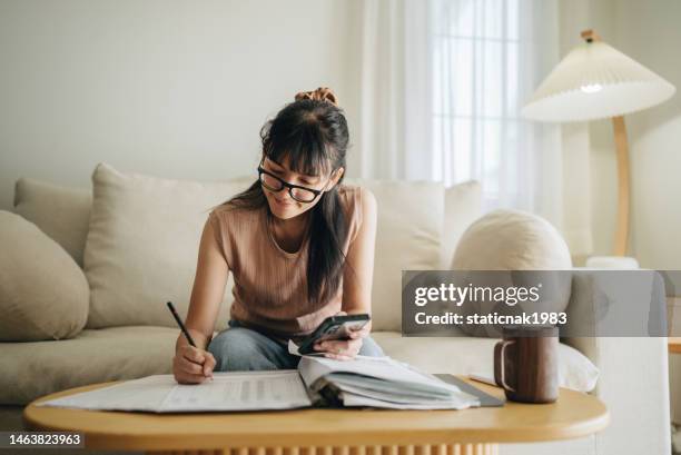 asian woman planning budget and using calculator on smartphone. - budget stockfoto's en -beelden