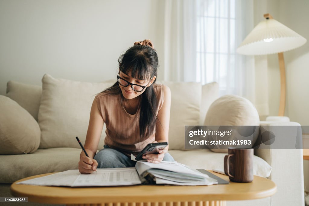 Asian woman planning budget and using calculator on smartphone.