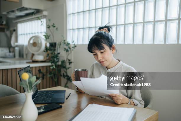 les femmes asiatiques travaillant avec des factures, calculent les dépenses en faisant du travail à la maison. - personal finance photos et images de collection