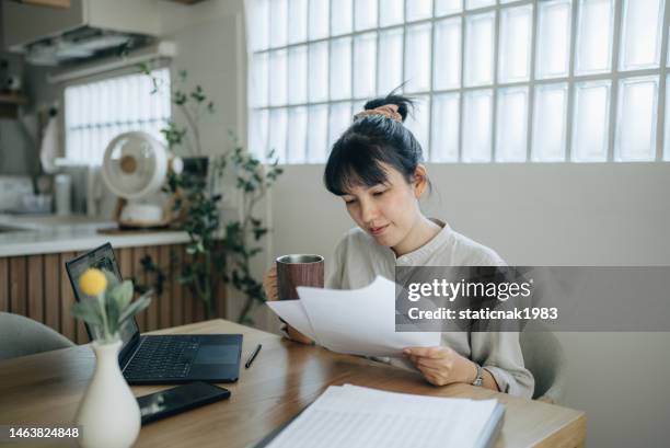 asian women working with invoices, calculates expenses doing work at home. - unique stock pictures, royalty-free photos & images