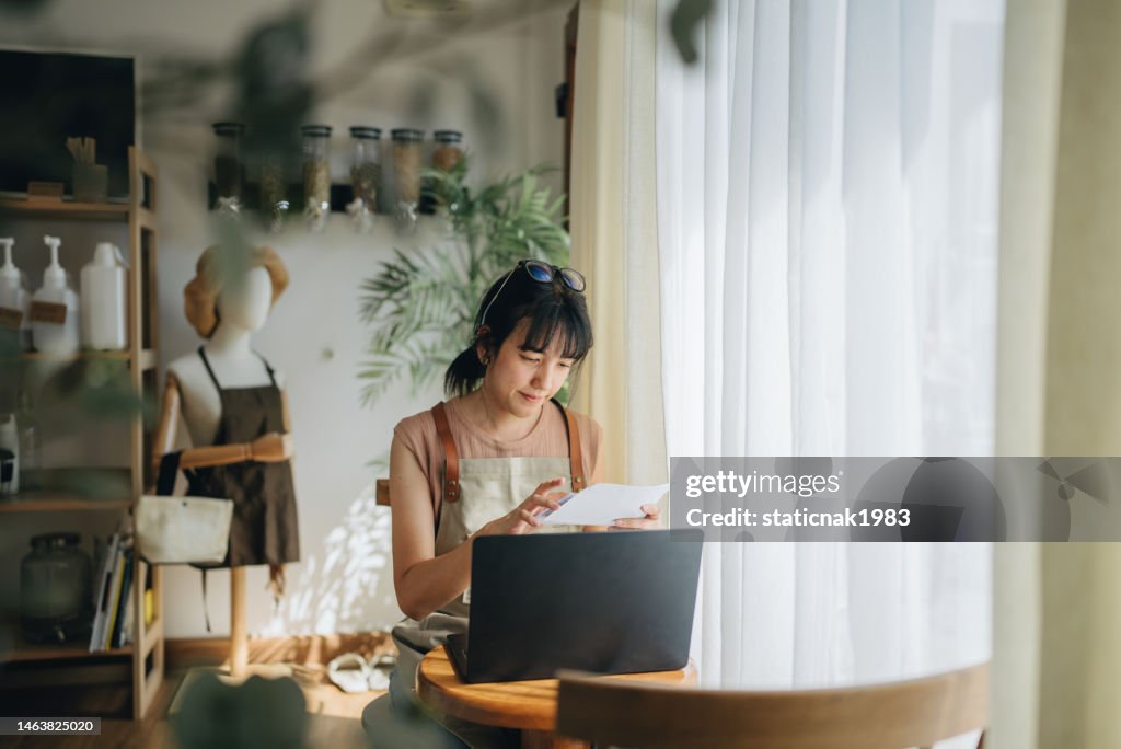 Young female small business owner making expenses at her store.