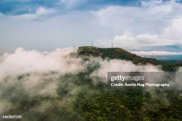 a green hill with windmills, covered by clouds - india rain stock-fotos und bilder