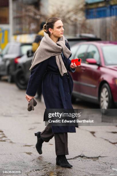 Guest wears a beige wool pullover knot at the waist, a navy blue belted trench coat, silver rings, a brown wool gloves, dark brown suit pants, black...