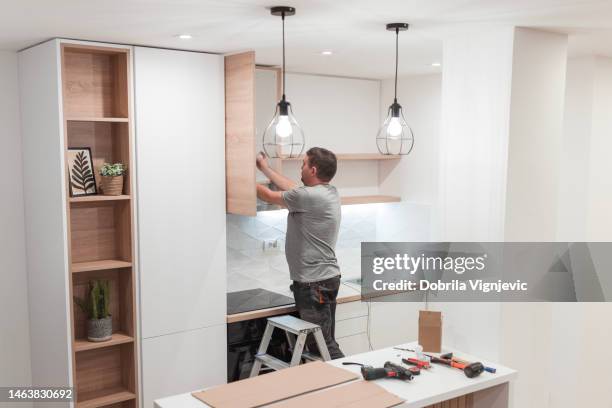 handyman working on kitchen cabinets while climbing the ladder - kitchen straighten stock pictures, royalty-free photos & images