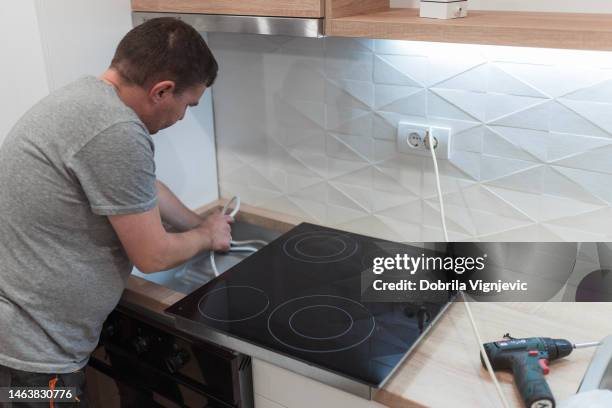 electrician handling stove cables - hob stock pictures, royalty-free photos & images
