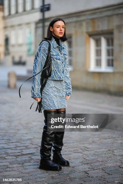 Guest wears silver earrings, a black turtleneck pullover, a blue denim with white ripped pattern jacket, a matching blue denim with white ripped...