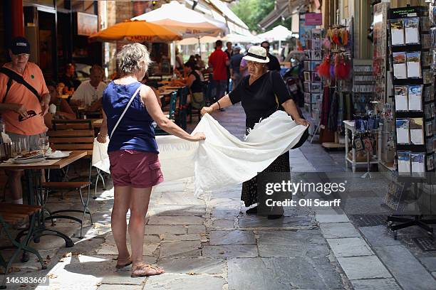 Street vendor sells a tourist woman a blanket outside a cafe in the district of Plaka on June 15, 2012 in Athens, Greece. The Greek electorate are...