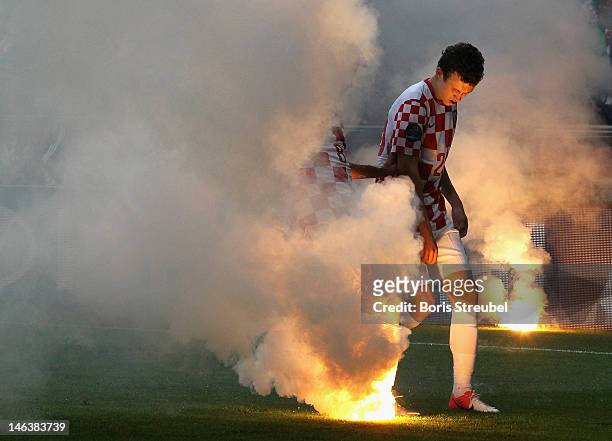 Ognjen Vukojevic and Ivan Perisic of Croatia trie to extinguish a flare on the pitch during the UEFA EURO 2012 group C match between Italy and...