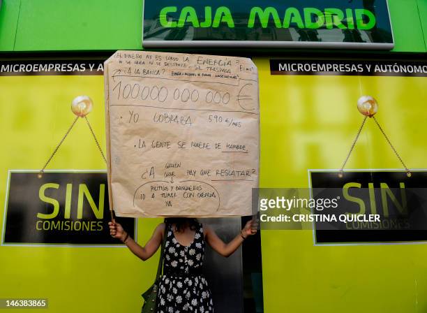 Woman holds a placard reading "People are starving" during a demonstration in front of a Bankia office in Sevilla, on June 15, 2012. Spain's...