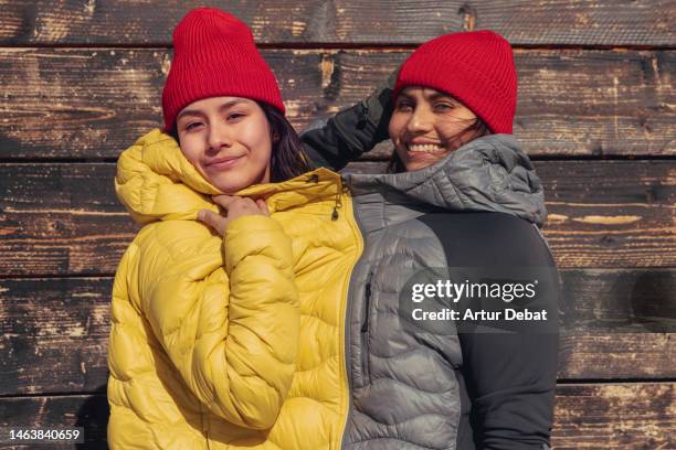 creative picture of latin women enjoying winter days with padded jackets hooked each other. - andorra people stock pictures, royalty-free photos & images