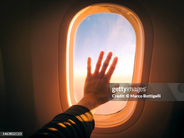 touching plane window while flying in the sky during sunset - explorador imagens e fotografias de stock
