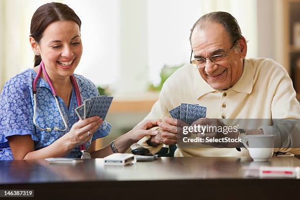 nurse and elderly man playing cards - senior men playing cards stock pictures, royalty-free photos & images