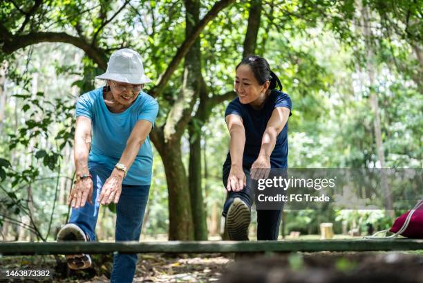 mutter und tochter strecken sich im öffentlichen park - beautiful asian legs stock-fotos und bilder