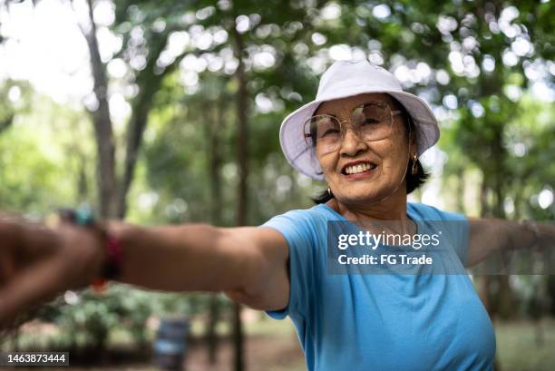portrait of a senior woman stretching on the public park - senior yoga lady stock pictures, royalty-free photos & images