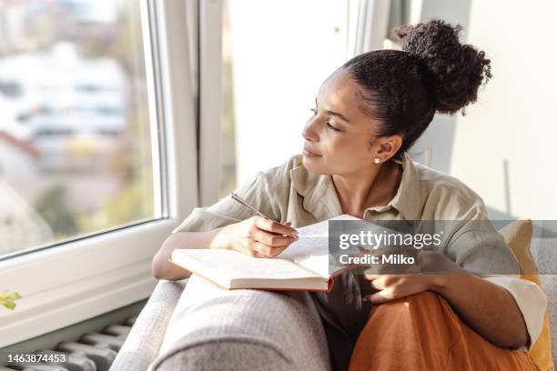 young african american woman writing notes - journal stockfoto's en -beelden