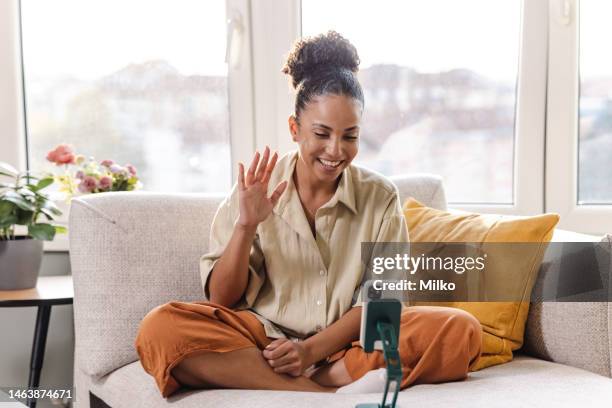 young charismatic woman sitting in front camera and recording a video - self recording stock pictures, royalty-free photos & images