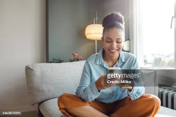 una giovane bella donna che usa uno smartphone a casa - looking at phones foto e immagini stock