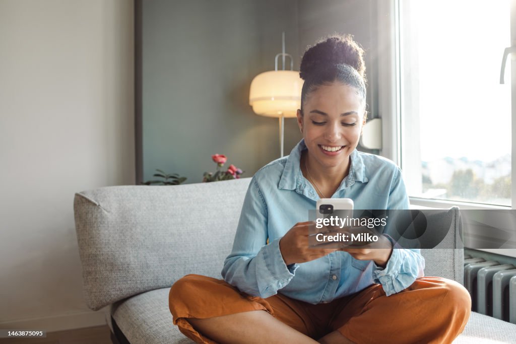 A young beautiful woman using a smart phone at home