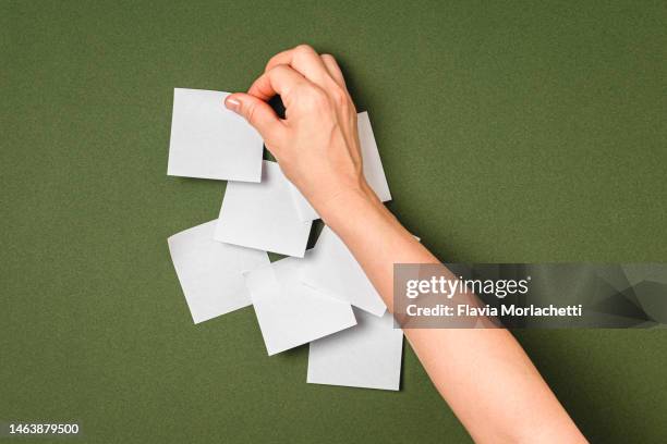 hand pasting adhesive note on green background - collant description physique photos et images de collection