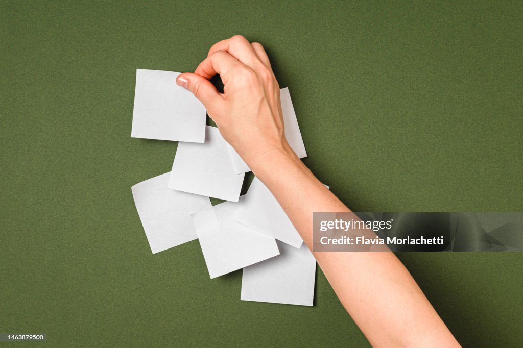 Hand pasting adhesive note on green background