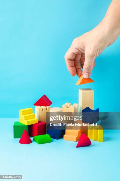 hand placing the last multicolored wooden block - woman picking up toys stock pictures, royalty-free photos & images