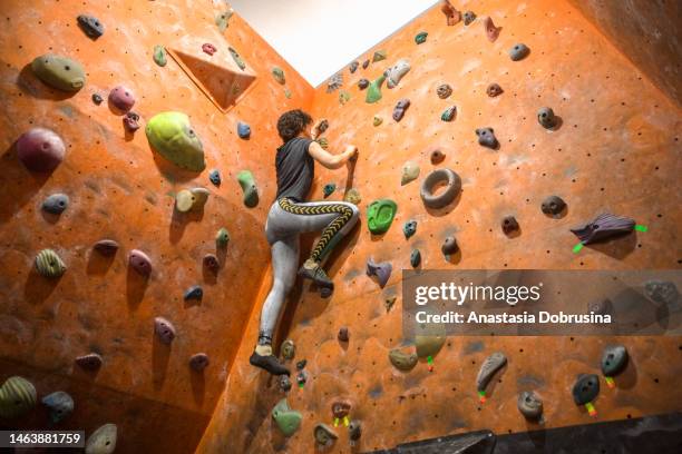 woman practicing rock climbing at an indoor climbing gym - sportsperson stock pictures, royalty-free photos & images