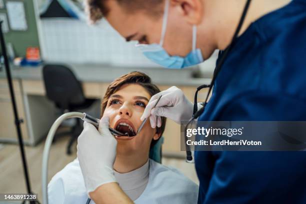 male dentist repairing the teeth of a young woman - wortelkanaal stockfoto's en -beelden