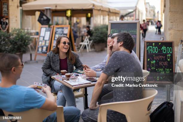 young people are sitting in the street cafe and they are talking and laughing. - historical geopolitical location stock pictures, royalty-free photos & images