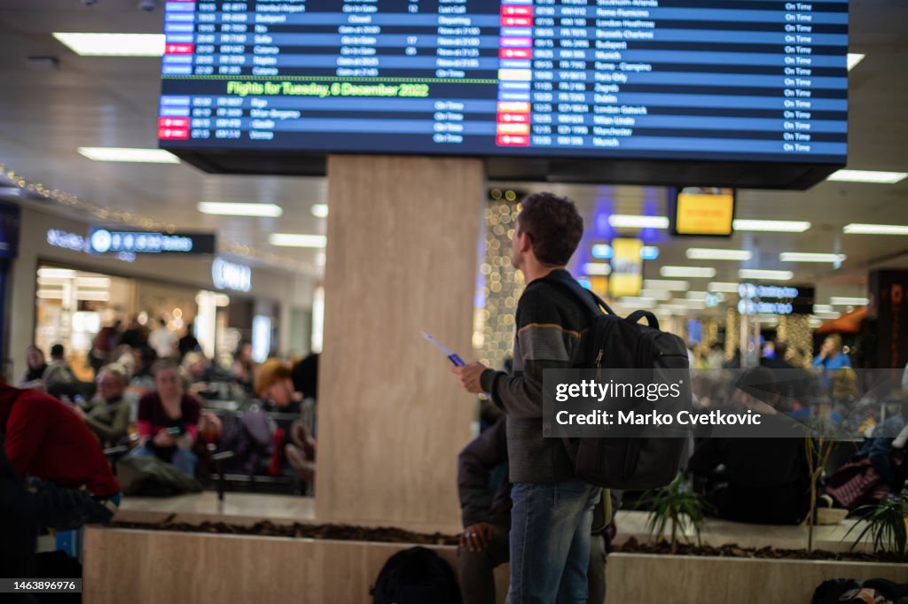 Il giovane è all'aeroporto e sta cercando il suo volo al tabellone degli orari