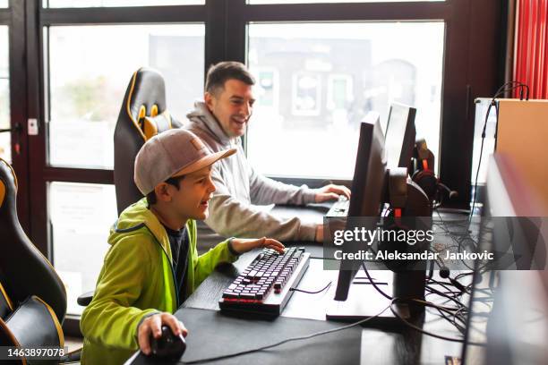 a cute boy having a great time playing pc games with his dad - game room 個照片及圖片檔