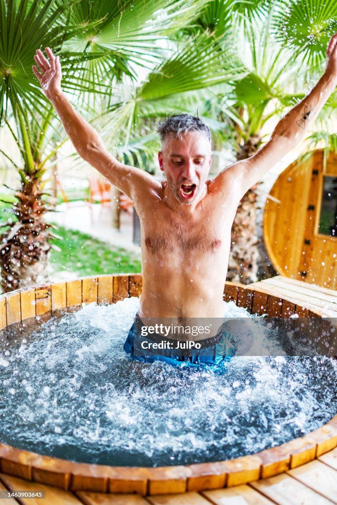 Junger erwachsener Mann springt in Outdoor Hot Tube