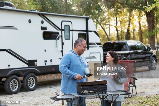 mature multiracial couple at rv park, grilling - couple grilling stock pictures, royalty-free photos & images