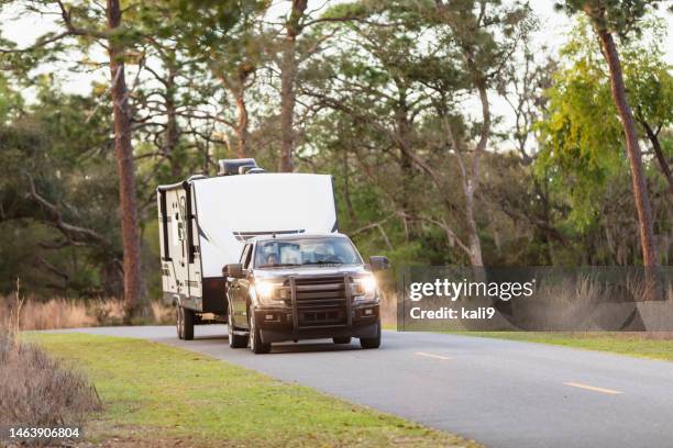 couple driving camper trailer on rural road - utility trailer stock pictures, royalty-free photos & images