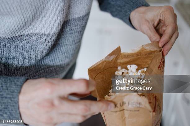 man opens a bag of microwave popcorn - salty snack stock pictures, royalty-free photos & images