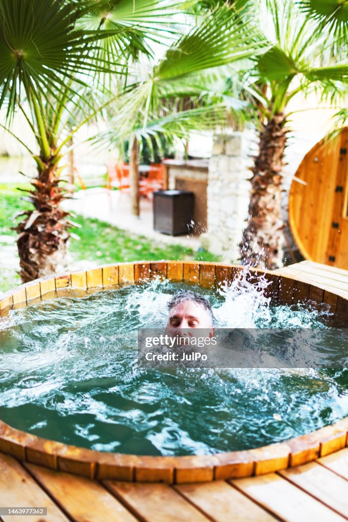 Junger erwachsener Mann springt in Outdoor Hot Tube