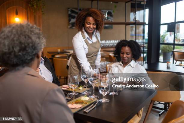 executive woman being served by waitress in sophisticated restaurant - gala table stock pictures, royalty-free photos & images