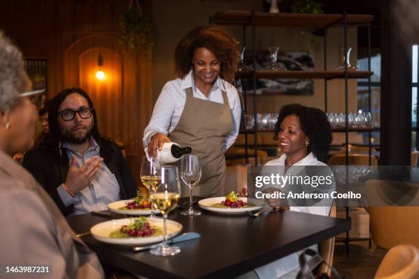 maitre d' serving wine to business people - wine gala stock pictures, royalty-free photos & images