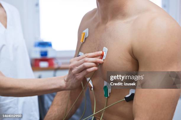 female doctor placing electrodes on patient's breast during ecography test in examination room - pulse trace stock pictures, royalty-free photos & images